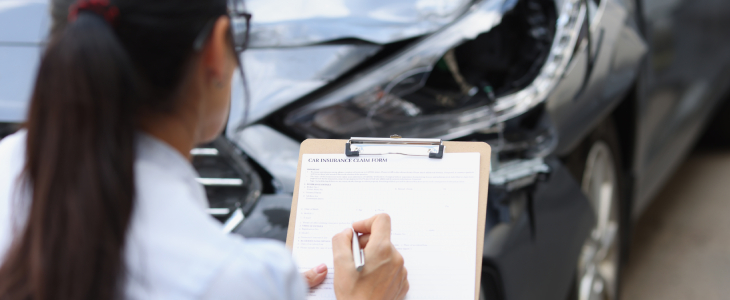 a woman holding a clipboard in front of a crashed car