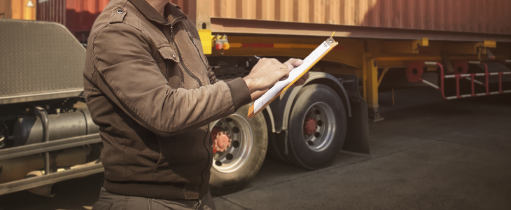 a man holding a clipboard next to a truck