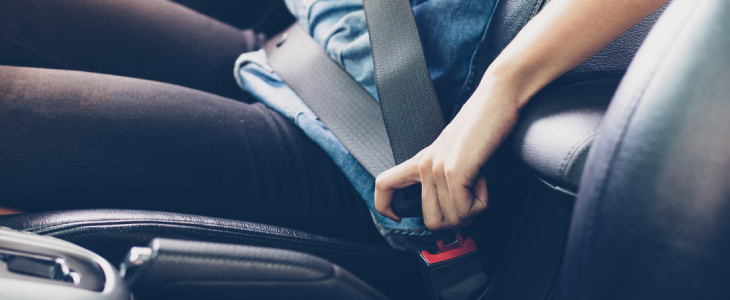 person buckling their seatbelt in the passenger side of a car