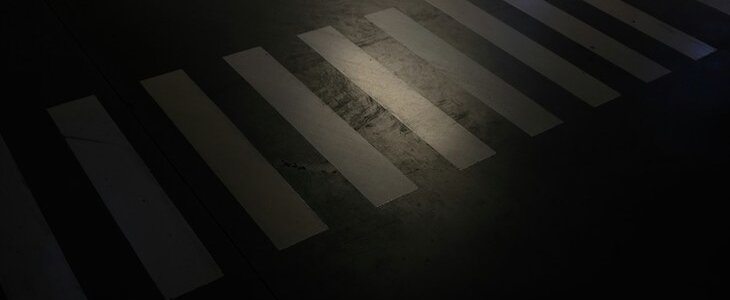 photo of empty crosswalk at night with single street light shining on it